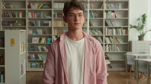 Teenage Guy in Books Store Library in High School College Looking at Camera Smiling Positive Showing
