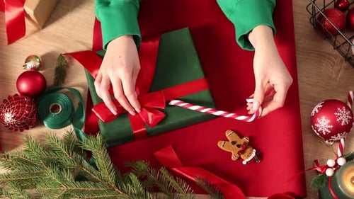 Woman wrapping Christmas gift at wooden table, top view