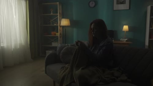Devastated Woman Sitting on a Sofa in a Dark Room A Woman Desperately Thinks About Personal Problems