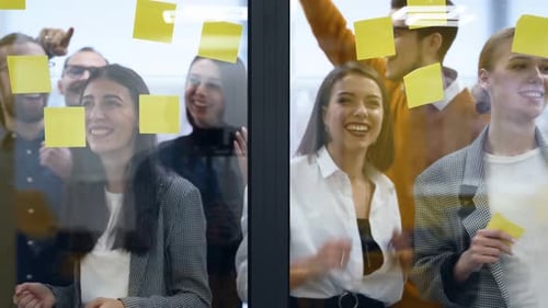 Business Team Brainstorm Writing Ideas on Paper Sticker Notes and Post It on Glass Wall Startup