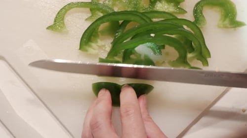 Close-Up of Hands Slicing Fresh Green Peppers in a Quiet Home Kitchen