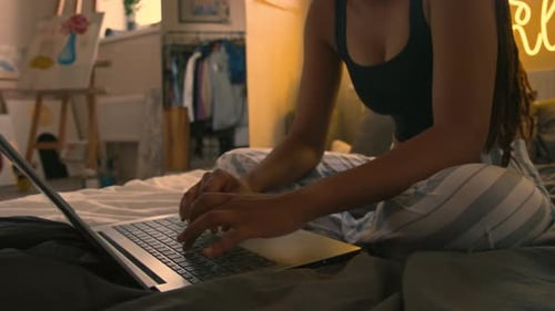 Young Woman Types on Laptop in Bedroom