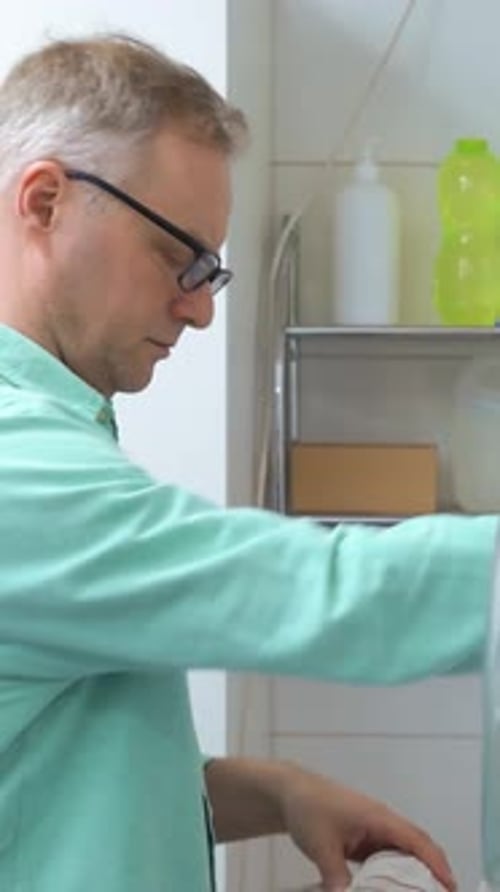 Man Loading Clothes Into Washing Machine