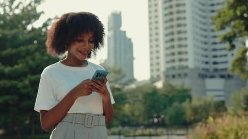 Young Woman Using Phone in Urban Park Setting
