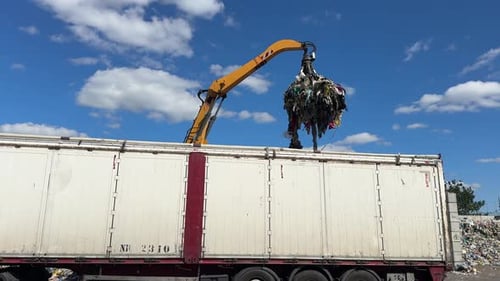 Crane loading debris into truck for disposal