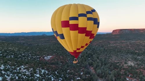 Hot Air Balloon Flying over Scenic Desert at Sunrise