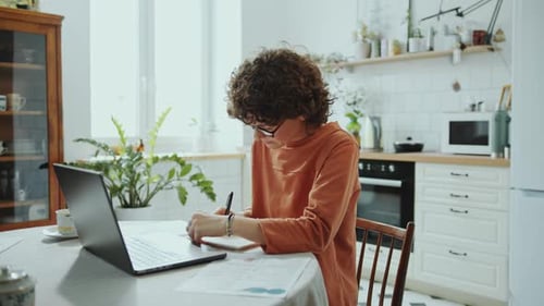 Woman Working with Laptop and Documents at Home