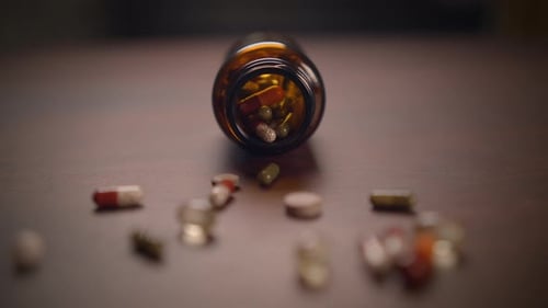 Pills and Capsules Spill from Medicine Bottle