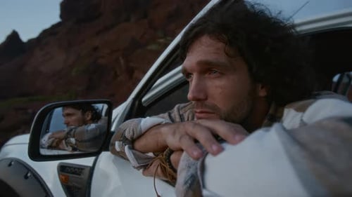 Man Looks Out From Truck in Desert