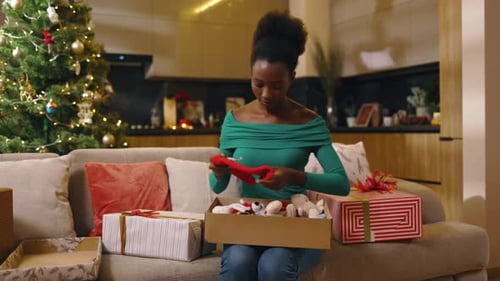 Woman Sorting Christmas Gifts on Sofa at Home