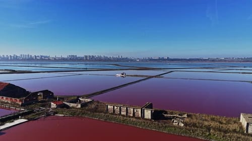 Salt pans in use near a city with water reflecting the sky