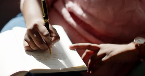 Close-up of an African American woman writing in a notebook at home