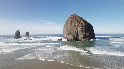 Haystack Rock looms over the waves at high tide