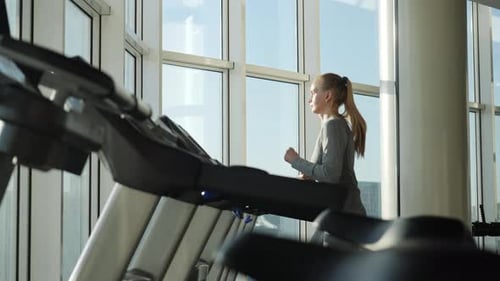 Attractive Woman of Middle Age is Running on Tread Mill in Sport Gym