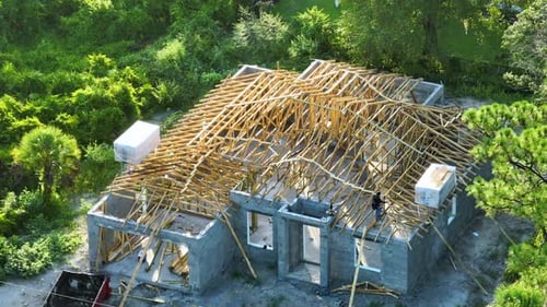 Aerial View of Unfinished Residential House with Wooden Roof Frame Structure Under Construction in