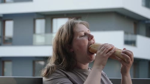 Woman Enjoying a Baguette Sandwich Outdoors