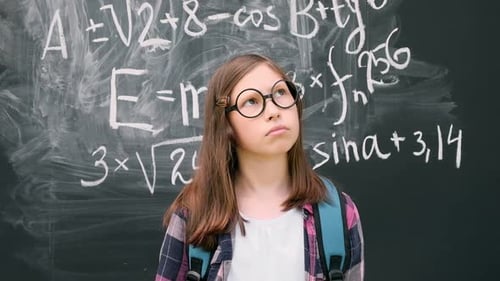 Young Student Standing in Front of Blackboard