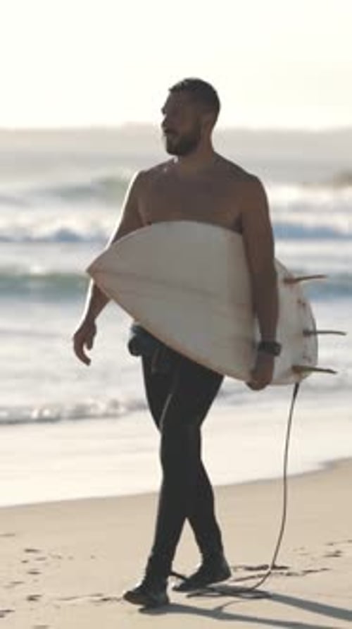 Man Walking with Surfboard on Sandy Beach