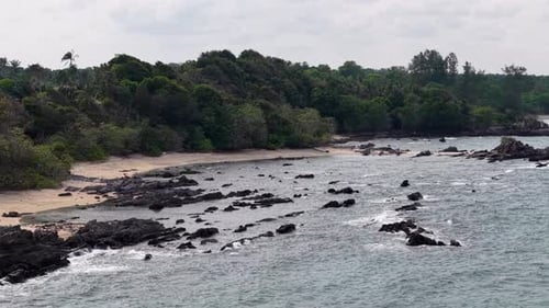 Waves crash over jagged black rocks