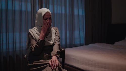 Sad Woman with Headscarf Sitting Indoors at Night