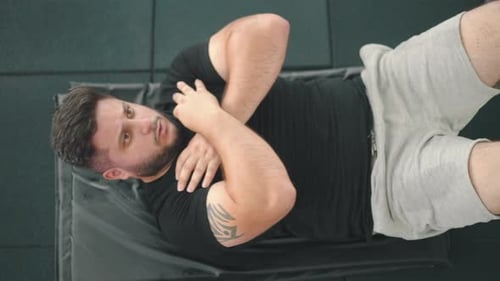 Top-Down-Aufnahme eines starken jungen Mannes, der im Fitnessstudio Crunches macht