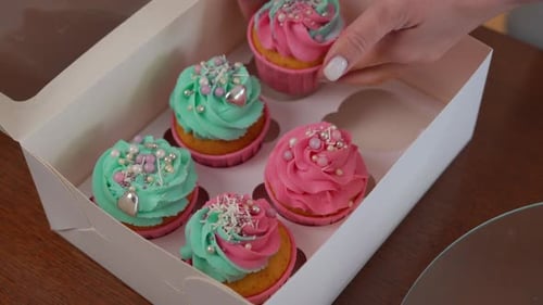 High Angle View Paper Box for Pastry Delivery and Female Caucasian Hands Placing Tasty Muffins