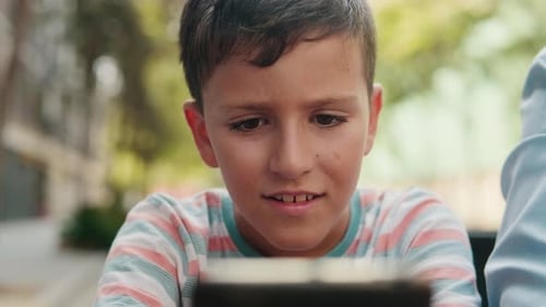 Young Boy using his smartphone in the park