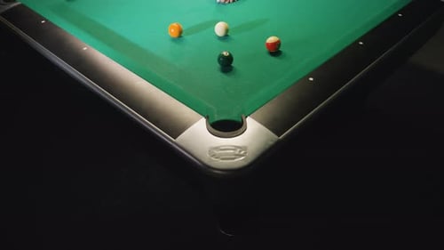 Nahaufnahme einer Hand mit dem Queue-Stick, um eine weiße Billardkugel zu schlagen