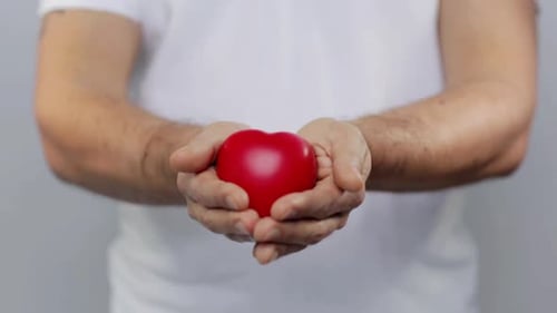 Man holds red heart shape in his hands