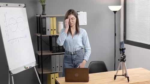 Young woman mentor recording presentation, webinar on smartphone standing on tripod