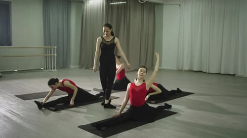Dance Students Stretching With Instructor in Studio