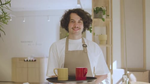 Cheerful Young Man Holding Tray with Two Coffee Mugs