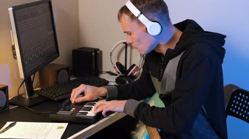 Man Creating Music on Keyboard at Desk