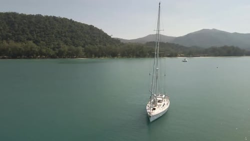 Aerial orbit view of sailing Yacht in ocean with Islands and ocean and mountains
