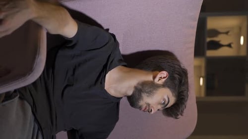 Vertical video of Depressed man lying on the sofa.