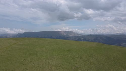 Large Grassy Hill with a Cloudy Sky in the Background