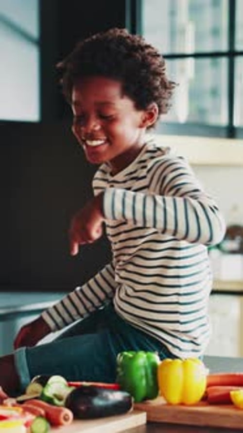 Boy Sitting on Kitchen Counter with Vegetables