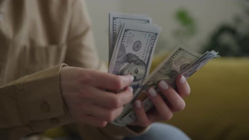 Woman Counting Stacks of 100 Dollar Bills