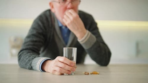 Senior Man Taking Medication with Water at Home