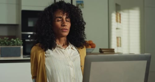 Creative Southeast Asian Woman Stretching at Her Desk While Working from Home on Laptop Comput