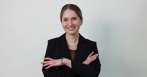 Confident Businesswoman Smiling with Arms Crossed Against a White Background