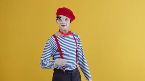 Ein junger Pantomime hebt seine Hand und zeigt mit dem Finger in die Kamera