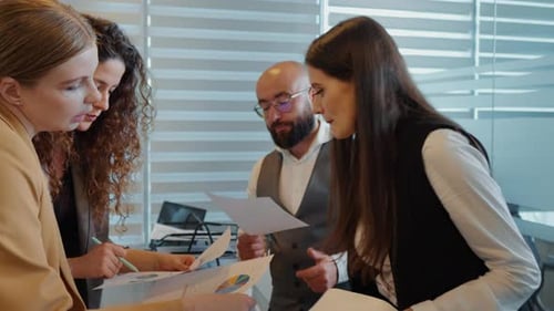 Three women and man working together planning success strategy enjoy teamwork in small office.