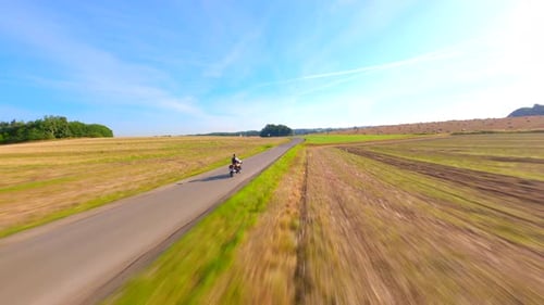 FPV Of Vintage Motorcycle Riding a Country Road Throught Fields In Summer