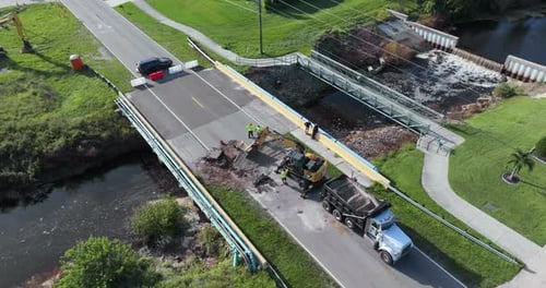 Straßenbaubagger repariert zerstörte Brücke, nachdem das Wasser durch die Hurrikanflut weggespült wurde
