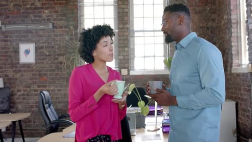 Happy diverse colleagues talking and drinking coffee in office in slow motion