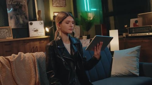Happy Young Woman Use of Tablet Computer Sitting on Sofa Smiling and Relax at Home Night Time