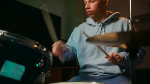 Un batteur appréciant son passe-temps en jouant énergiquement dans une pièce sombre exprimant sa passion et