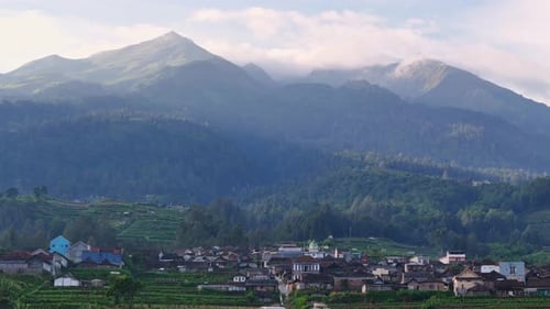 Aerial video captures a vibrant house of village and mountains peak in the background in the morning