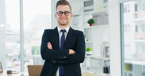 4k video footage of a young businessman standing with his arms crossed in an office